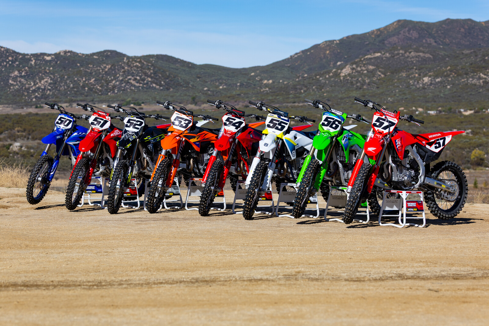 Motocross bikes lined up against a mountain backdrop